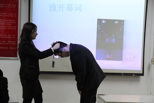 教员张老师为学员佩戴新听课证。-北大青鸟洛阳融科
